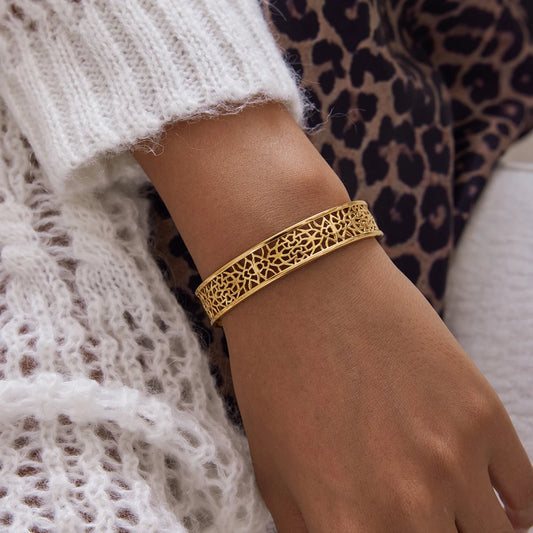 Gold bracelet on a wrist with a patterned background