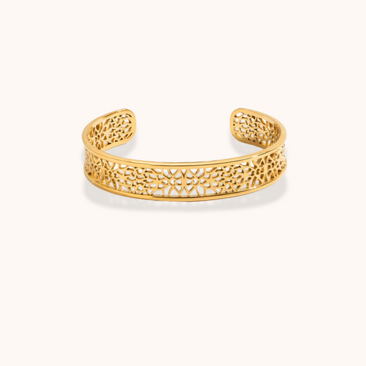 Gold bracelet with intricate design on a white background